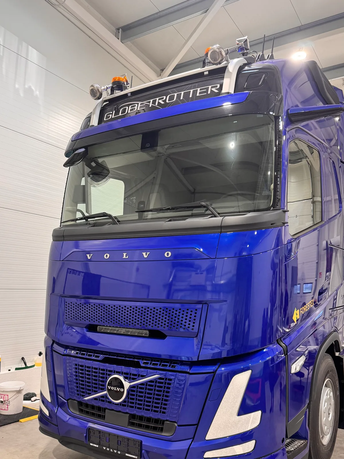 The blue Volvo FH Globetrotter from the proof job, photographed inside the PPF studio before its front end was patterned.